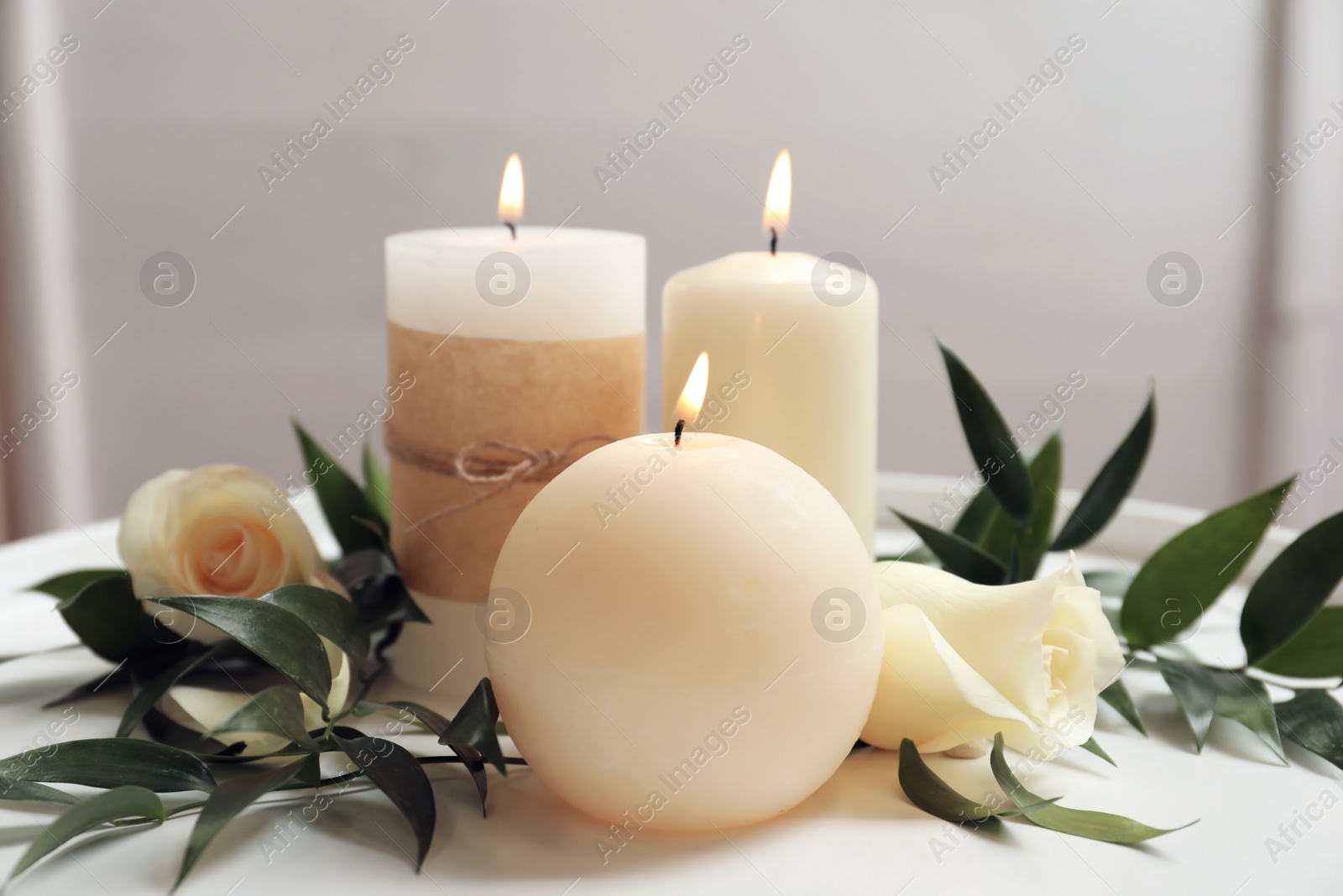 Photo of Beautiful composition with burning candles and flowers on table