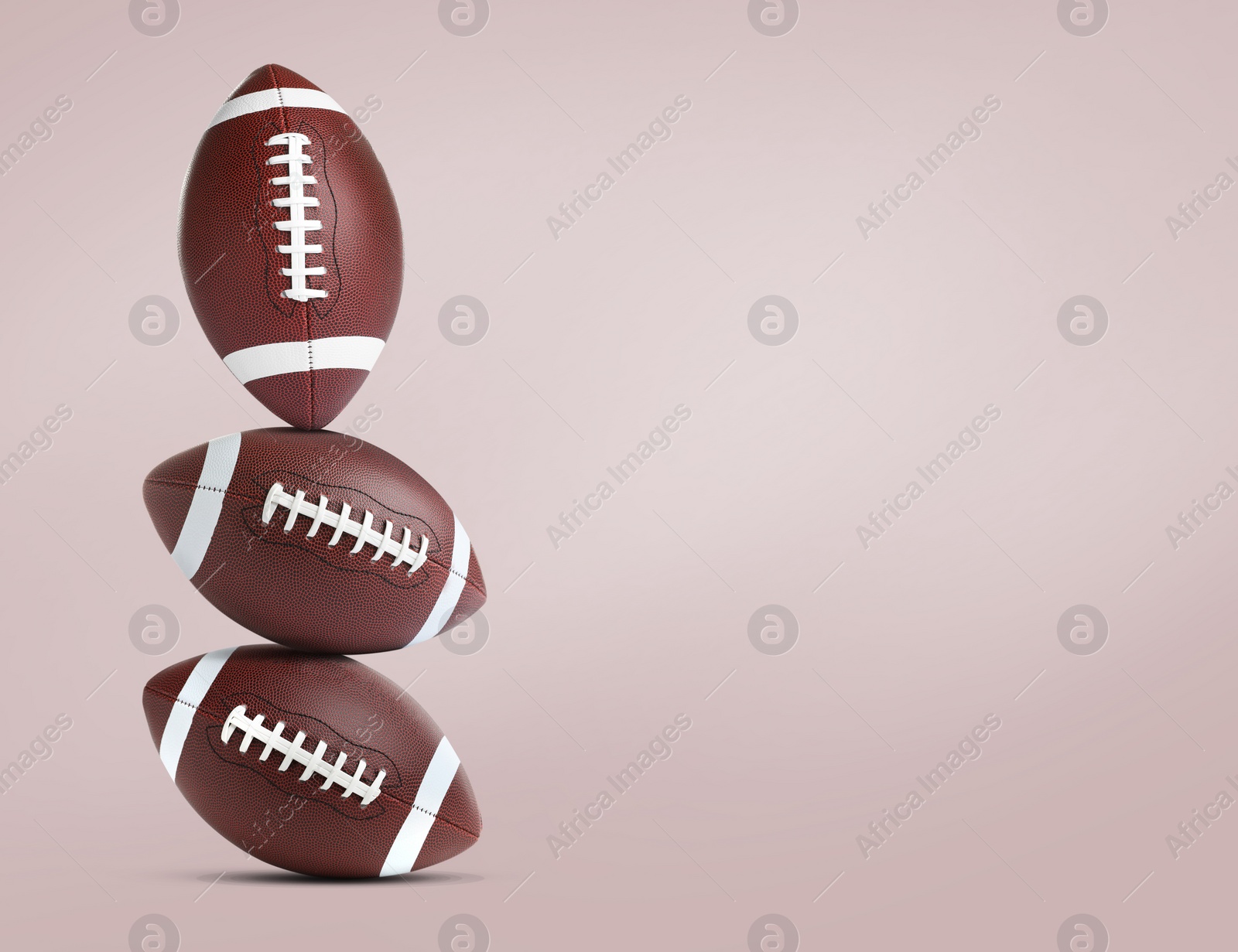 Image of Stack of American football balls on pale pink background. Space for text