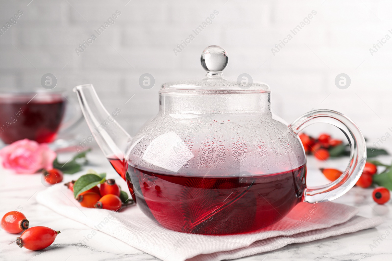 Photo of Fresh rose hip tea and berries on white marble table