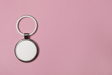 Photo of Metallic keychain with silver key ring on pale pink background, top view. Space for text
