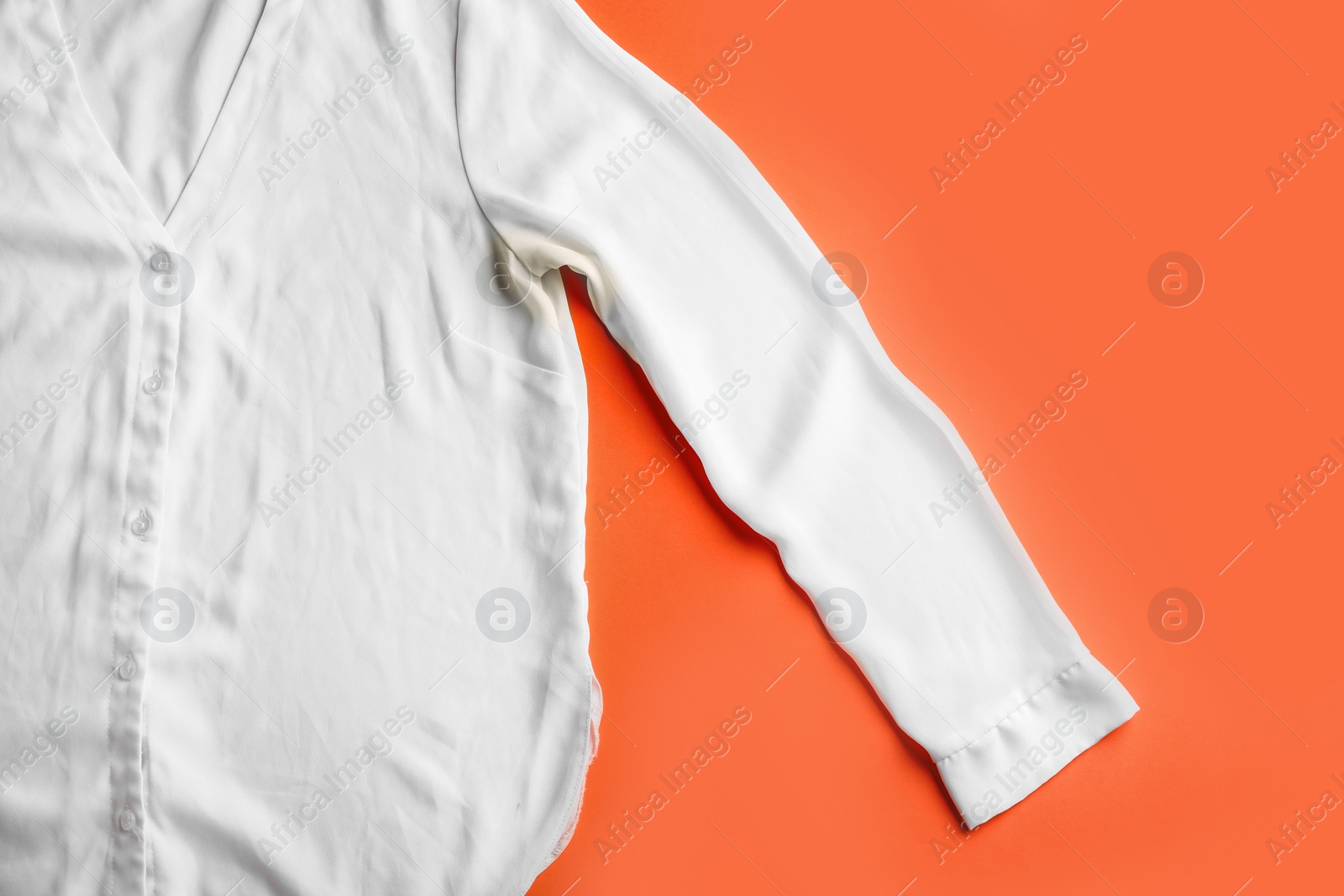 Photo of Shirt with deodorant stain on coral background, top view