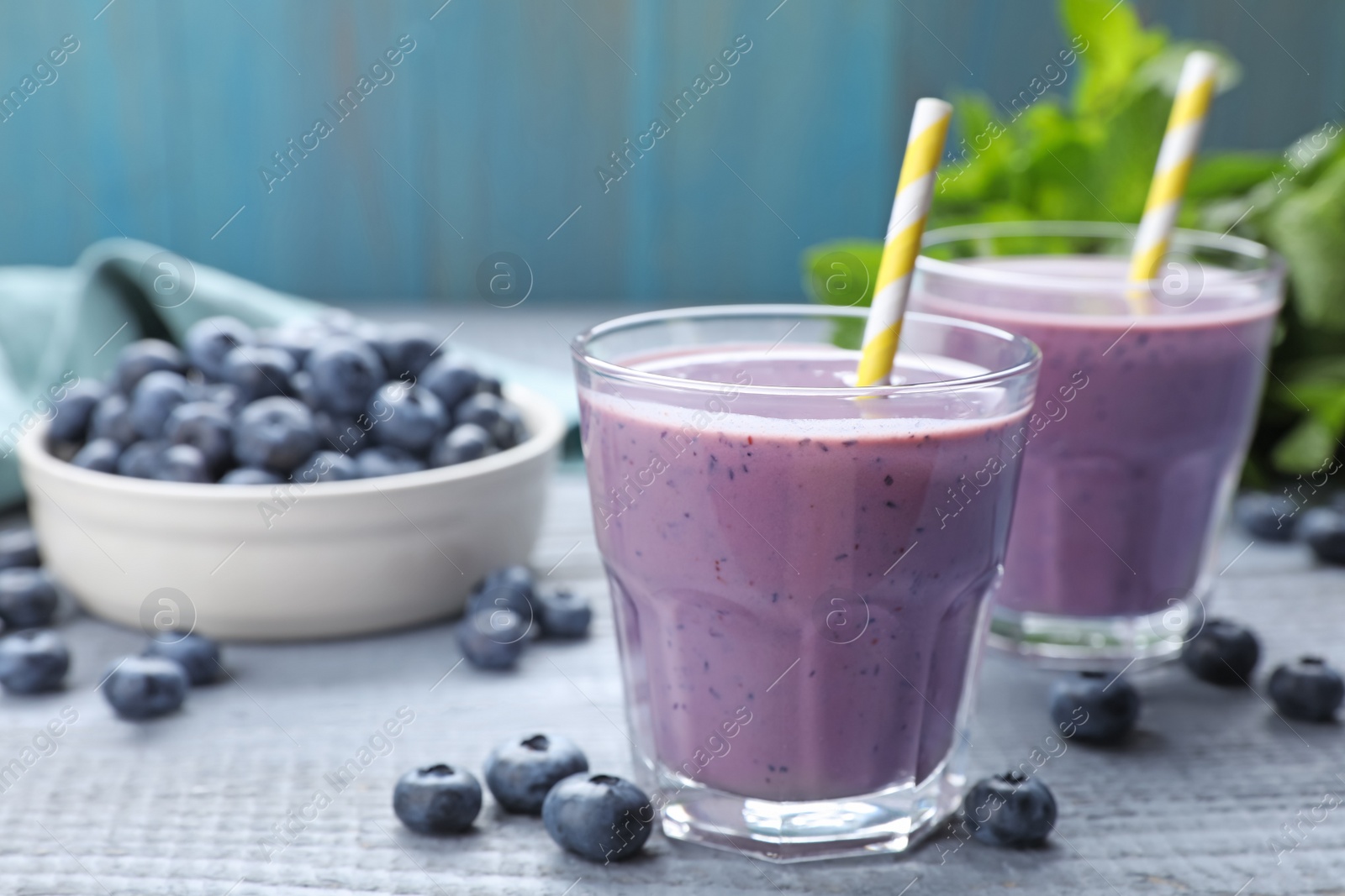 Photo of Freshly made blueberry smoothie on grey wooden table