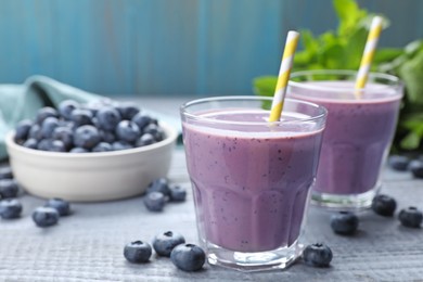 Photo of Freshly made blueberry smoothie on grey wooden table