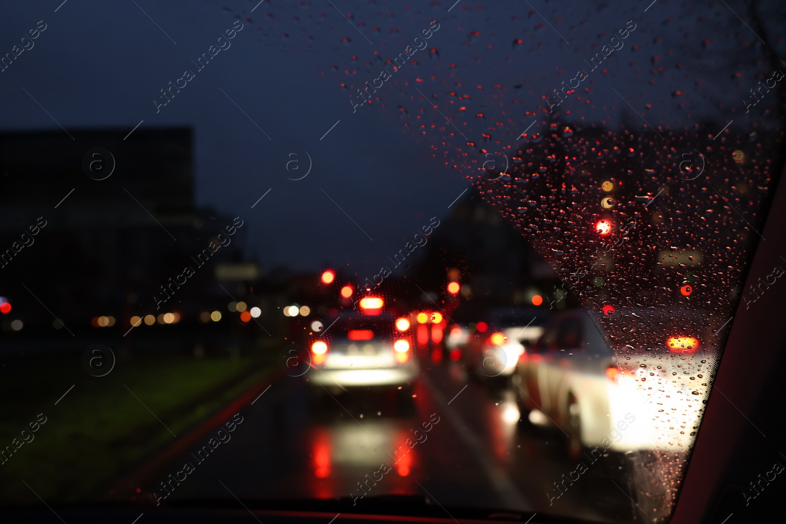 Photo of Blurred view of road through wet car window at night. Bokeh effect