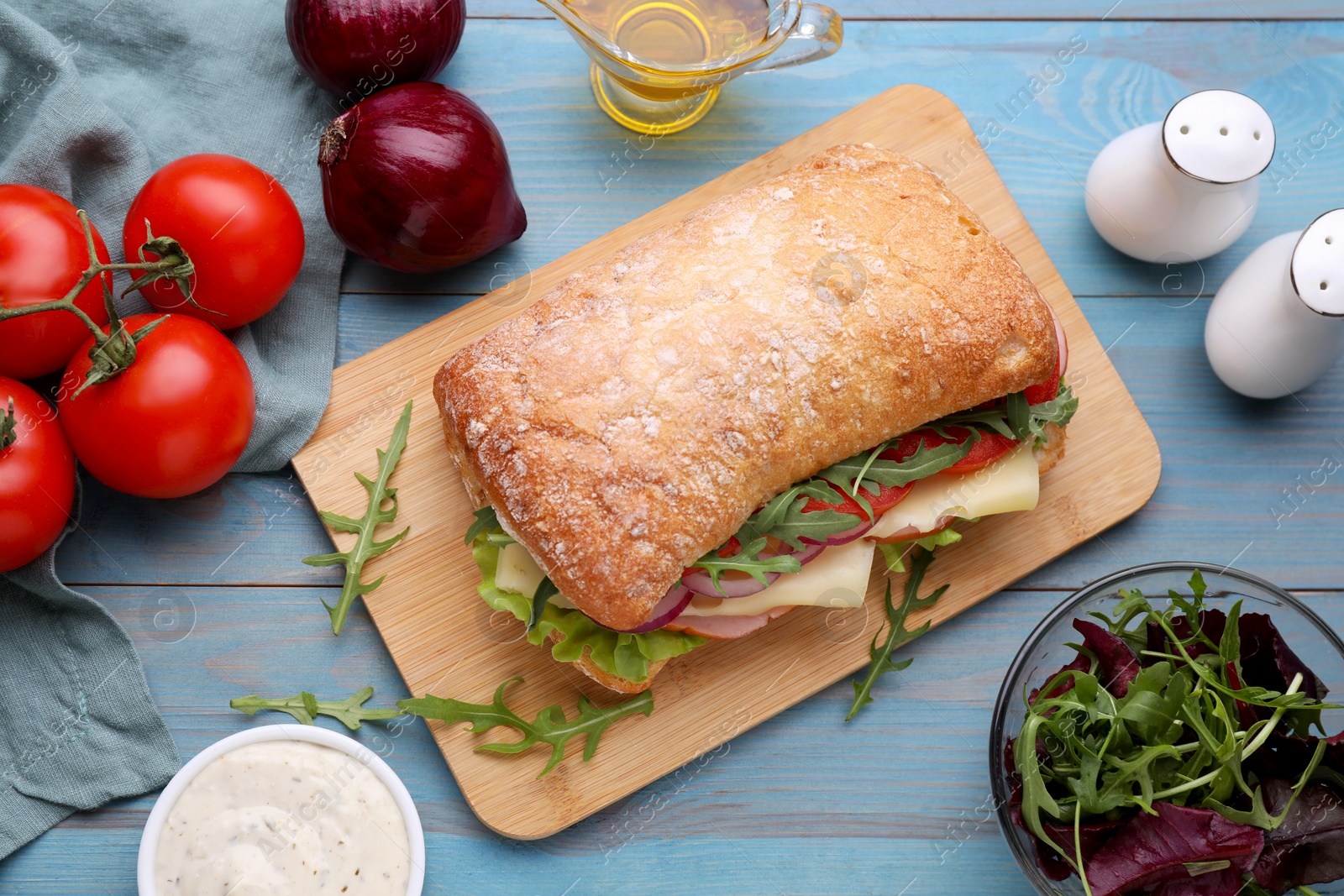 Photo of Delicious sandwich and fresh ingredients on light blue wooden table, flat lay