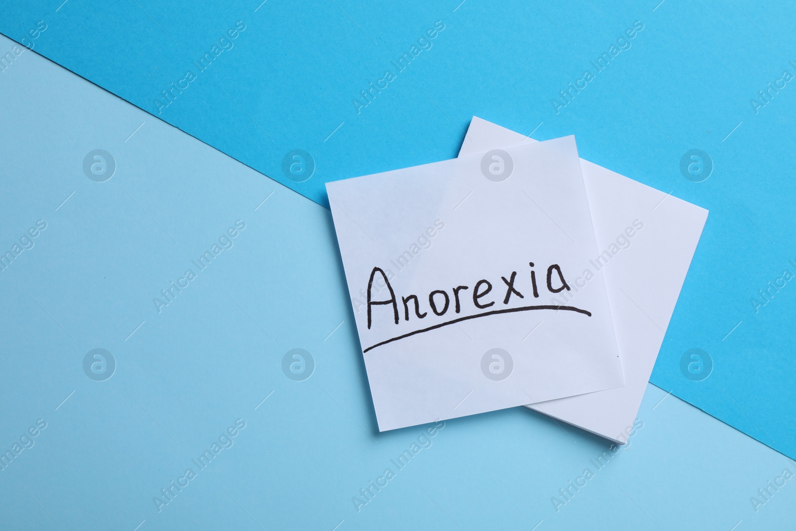 Photo of Note papers with word Anorexia on light blue background, flat lay. Space for text