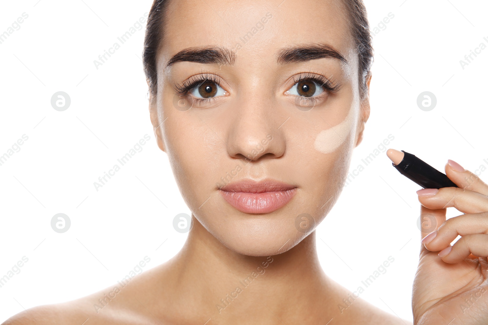 Photo of Young woman applying foundation on her face against white background