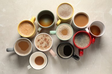 Photo of Many cups with different aromatic coffee on light grey marble table, flat lay
