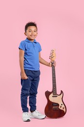 Photo of African-American boy with electric guitar on pink background