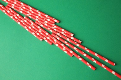 Paper drinking straws on green background, above view