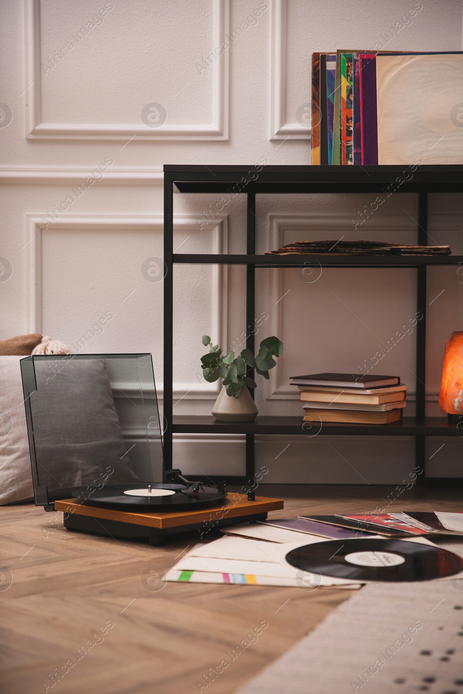 Photo of Stylish turntable with vinyl records on floor indoors