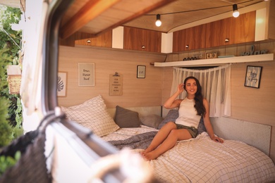Photo of Young woman on bed in trailer. Camping vacation