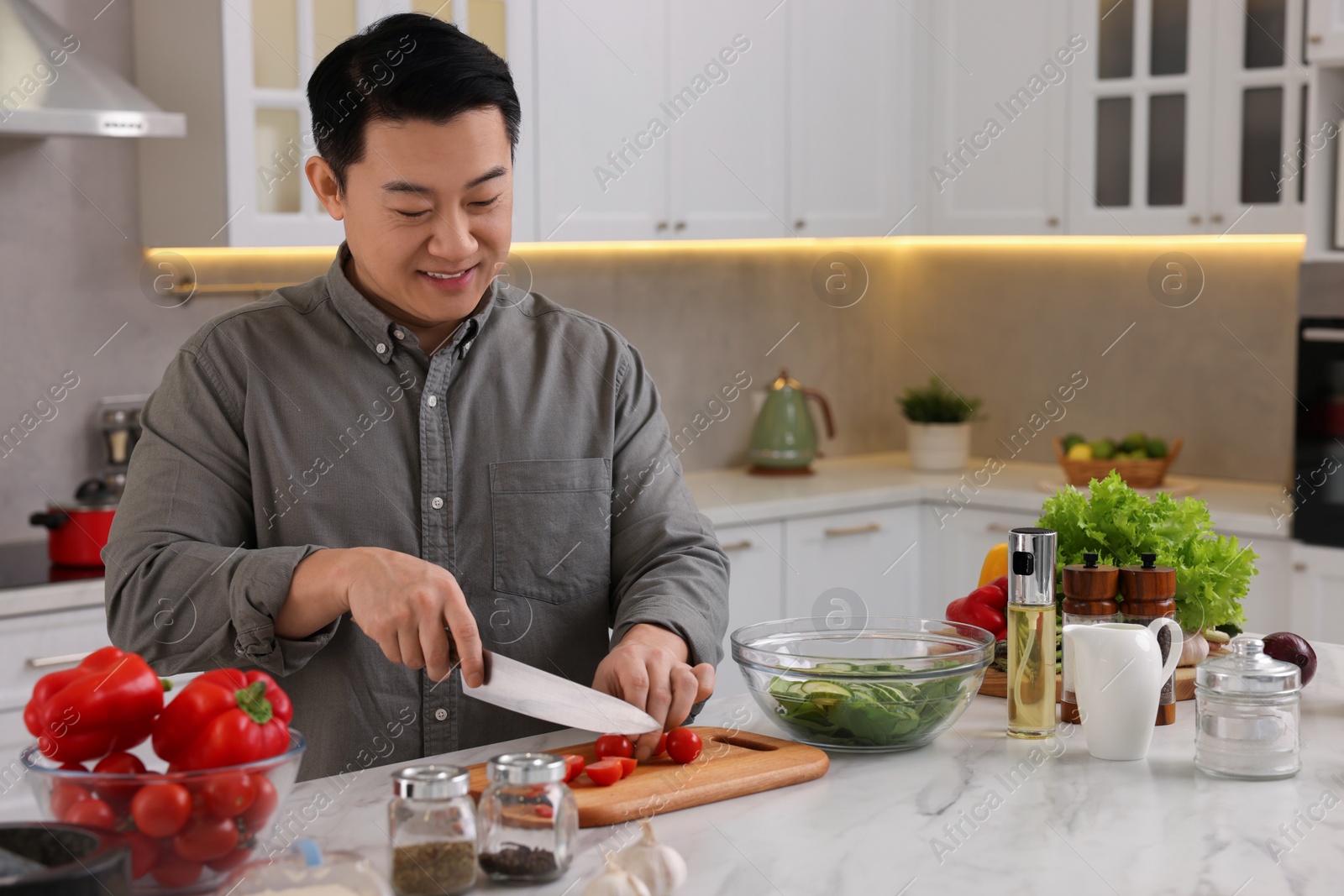 Photo of Cooking process. Man cutting fresh tomatoes at countertop in kitchen