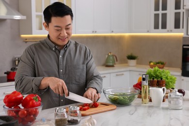 Cooking process. Man cutting fresh tomatoes at countertop in kitchen