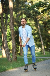 Young man roller skating in summer park