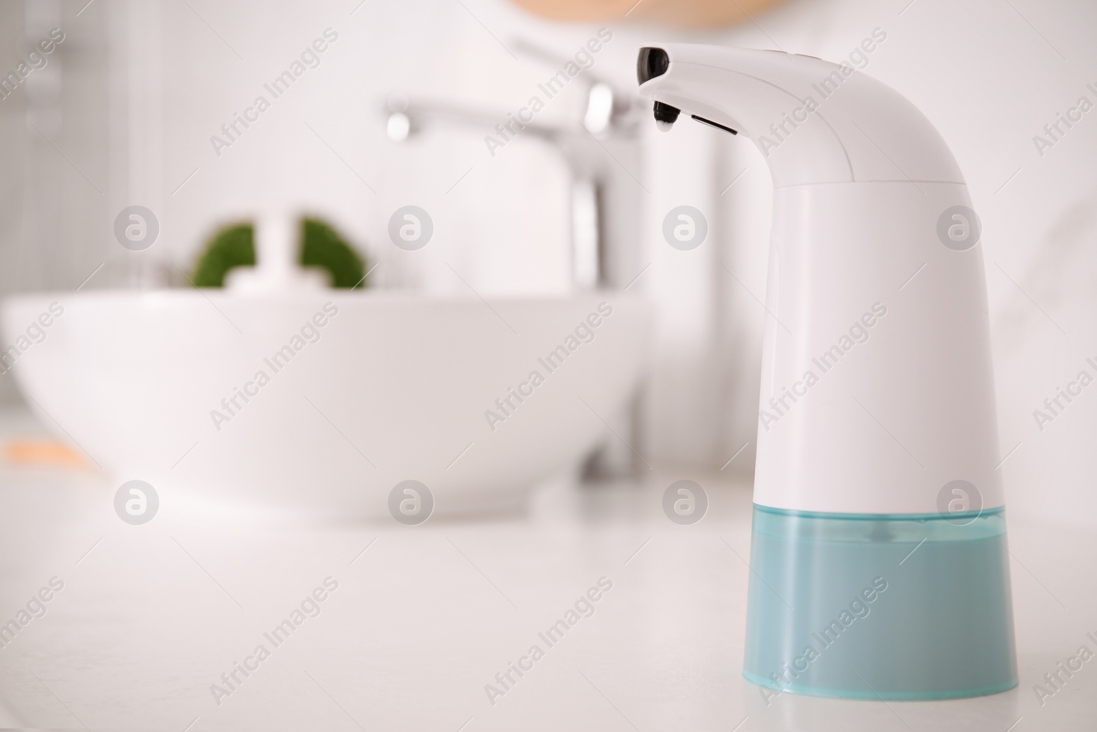 Photo of Modern automatic soap dispenser on countertop in bathroom. Space for text