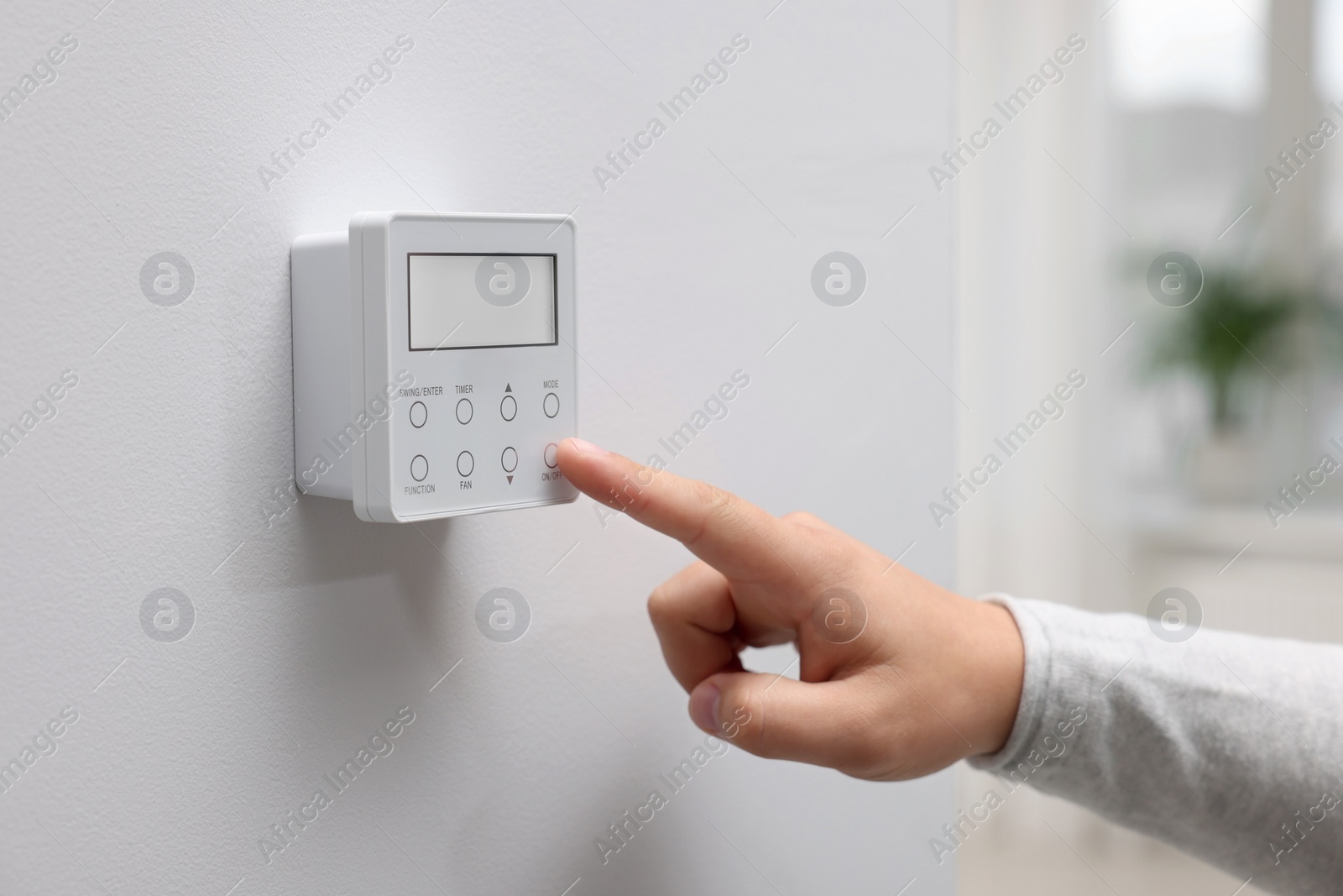 Photo of Woman adjusting thermostat on white wall indoors, closeup. Smart home system