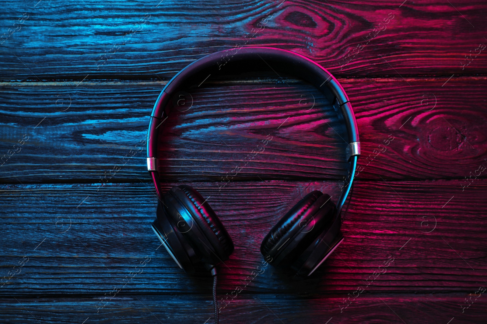 Photo of Stylish modern headphones with earmuffs on wooden background, top view