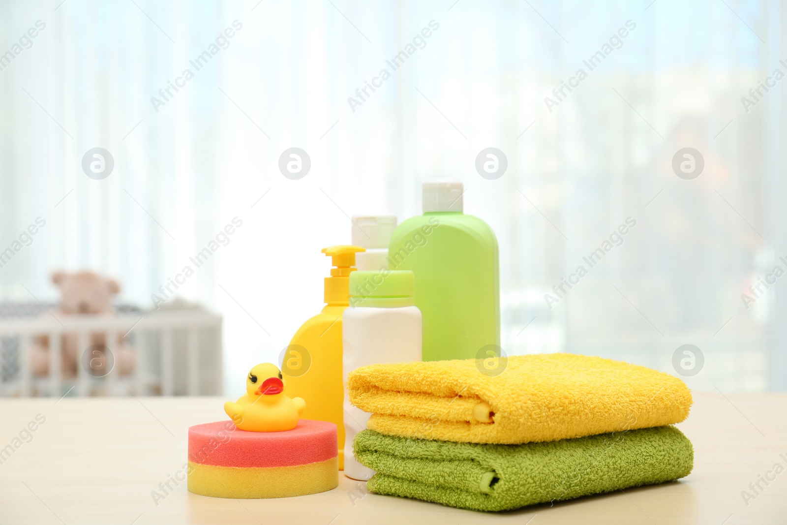 Photo of Baby cosmetic products, toy and towels on table indoors