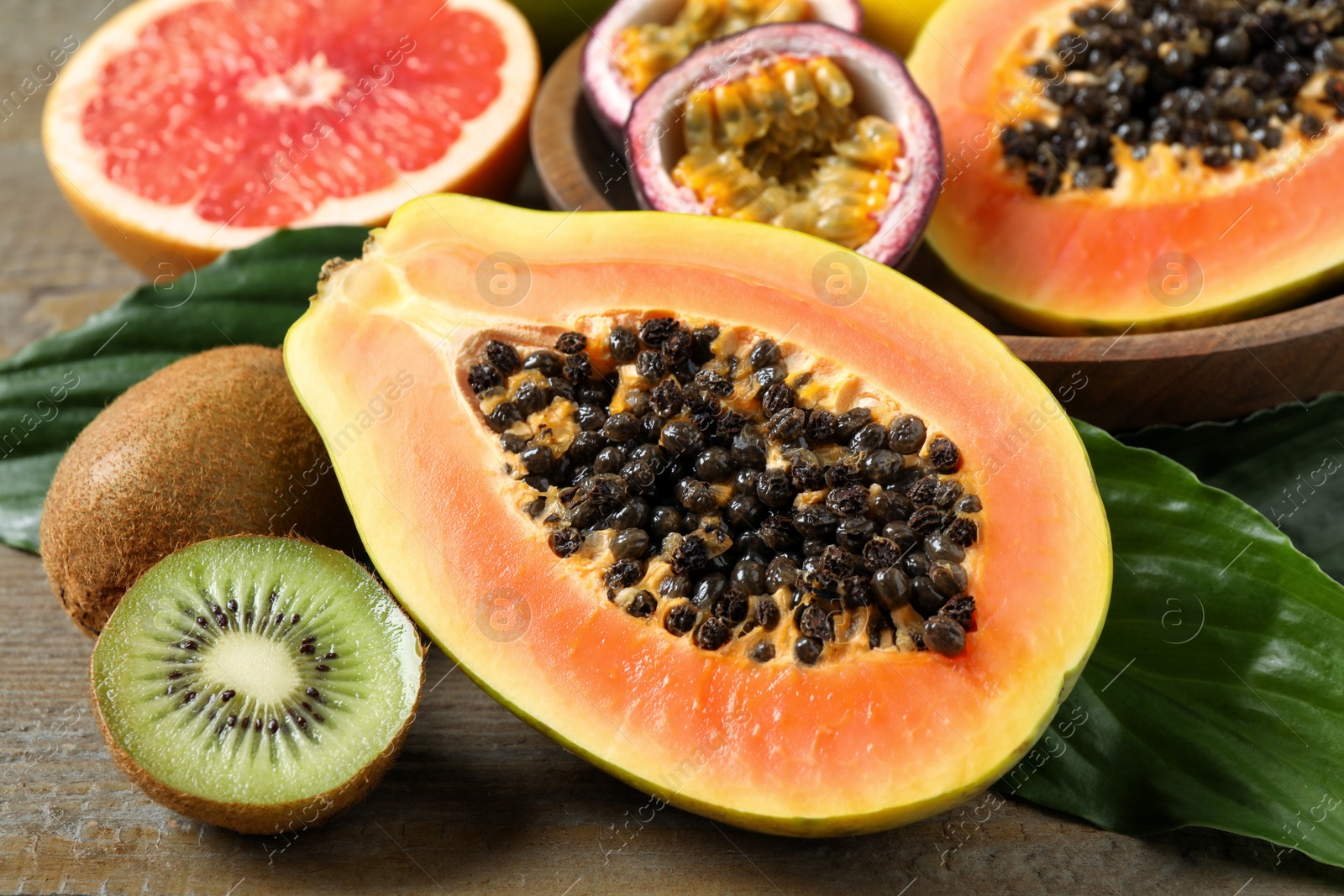 Photo of Fresh ripe papaya and other fruits on wooden table, closeup