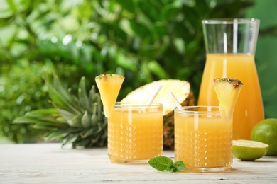 Photo of Composition with delicious pineapple juice on table against blurred background