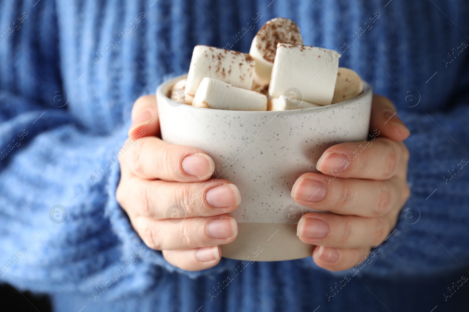 Photo of Woman holding cup of delicious hot cocoa with marshmallows, closeup. Winter drink