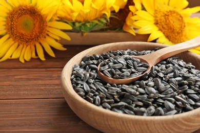 Photo of Bowl and spoon with sunflower seeds on table, closeup