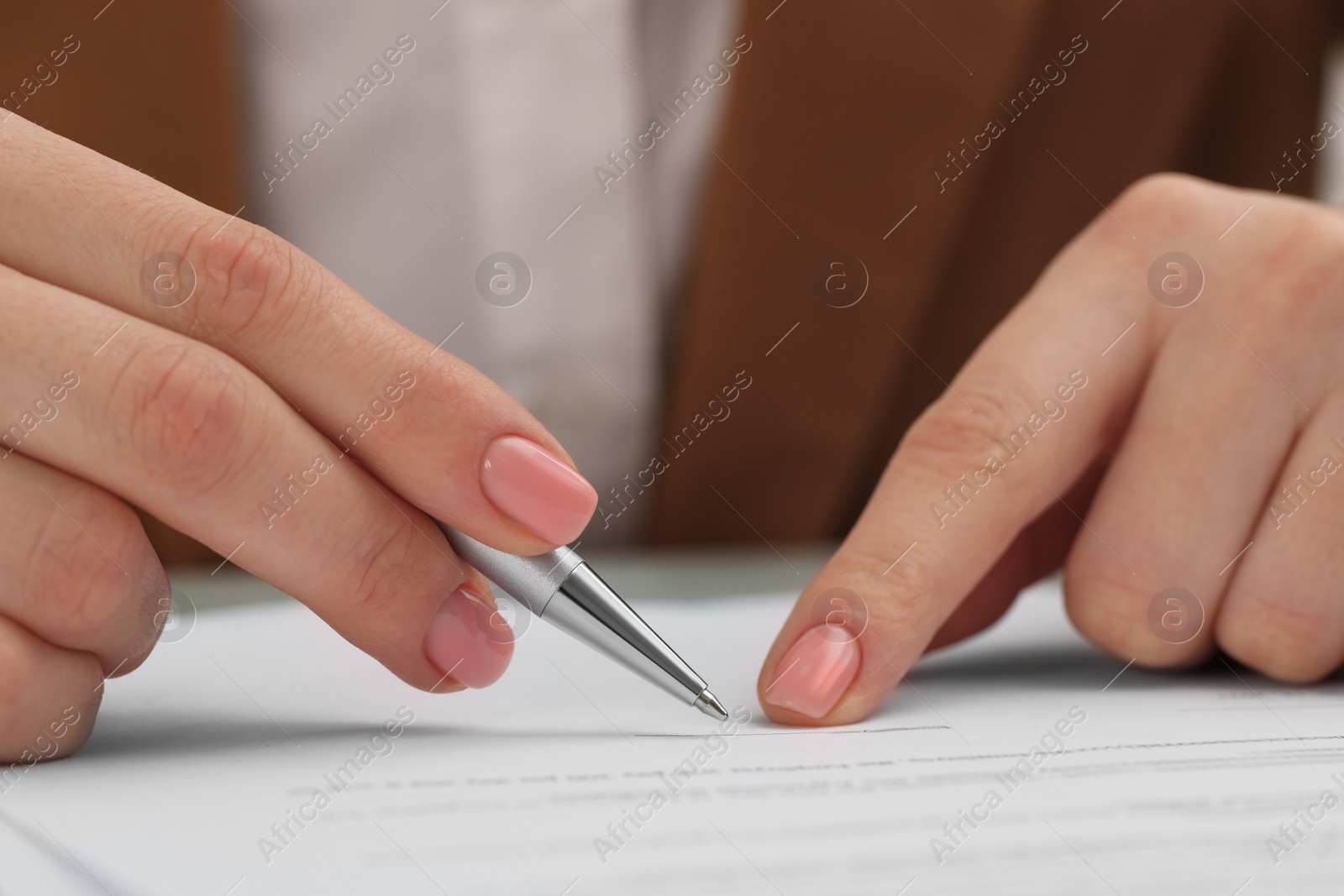 Photo of Woman signing document at table, closeup view