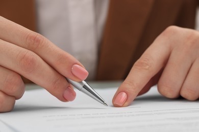 Woman signing document at table, closeup view