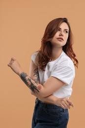 Portrait of beautiful tattooed woman on beige background