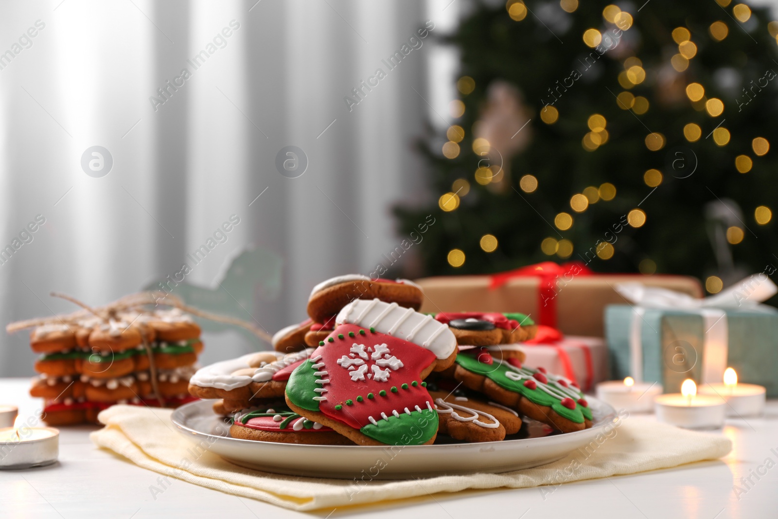 Photo of Decorated cookies on white table against blurred Christmas lights