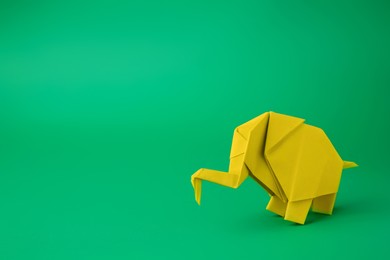 Photo of Origami art. Paper elephant on green background, space for text