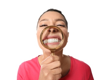 Young woman with healthy teeth and magnifier on white background