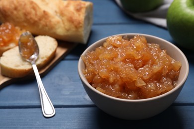 Photo of Bowl with delicious apple jam on blue wooden table, closeup