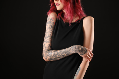 Photo of Beautiful woman with tattoos on arms against black background, closeup