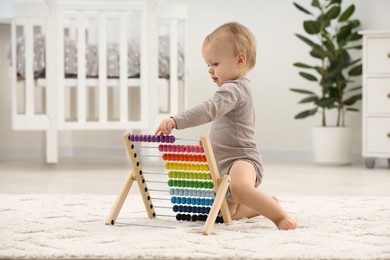 Photo of Children toys. Cute little boy playing with wooden abacus on rug at home