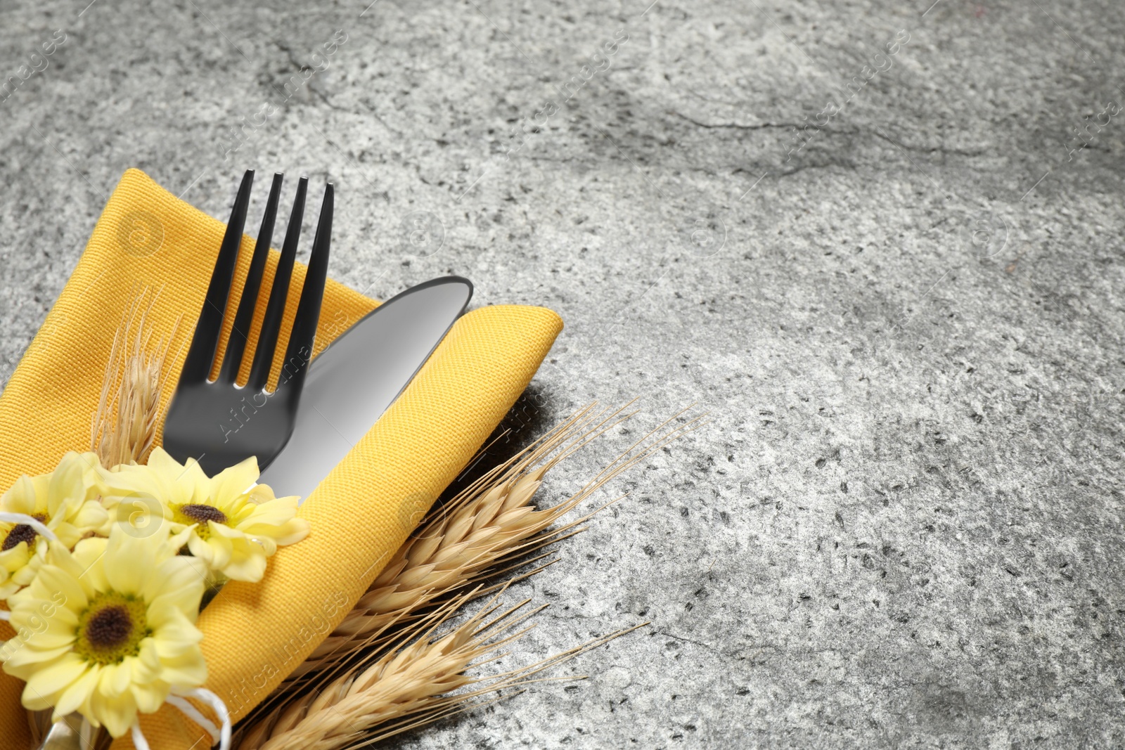 Photo of Cutlery, spikelets and flowers on grey background, closeup with space for text. Thanksgiving Day celebration