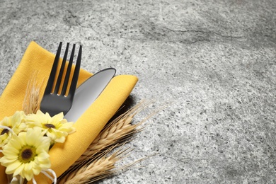 Cutlery, spikelets and flowers on grey background, closeup with space for text. Thanksgiving Day celebration