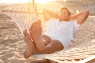 Photo of Man relaxing in hammock outdoors at sunset, focus on legs