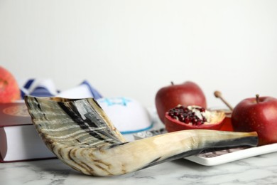 Photo of Composition with Rosh Hashanah holiday symbols on white marble table, closeup. Space for text