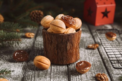 Photo of Homemade walnut shaped cookies with boiled condensed milk, fir branches and cones on wooden table