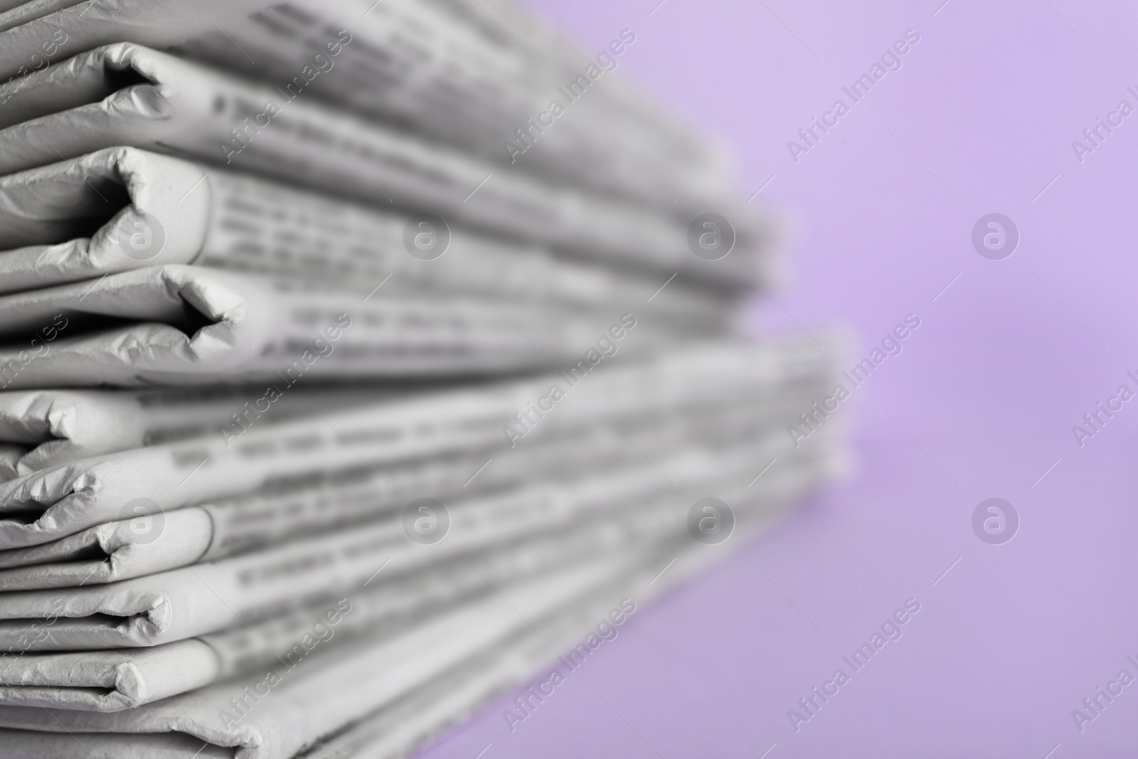 Photo of Stack of newspapers on light violet background, closeup. Journalist's work