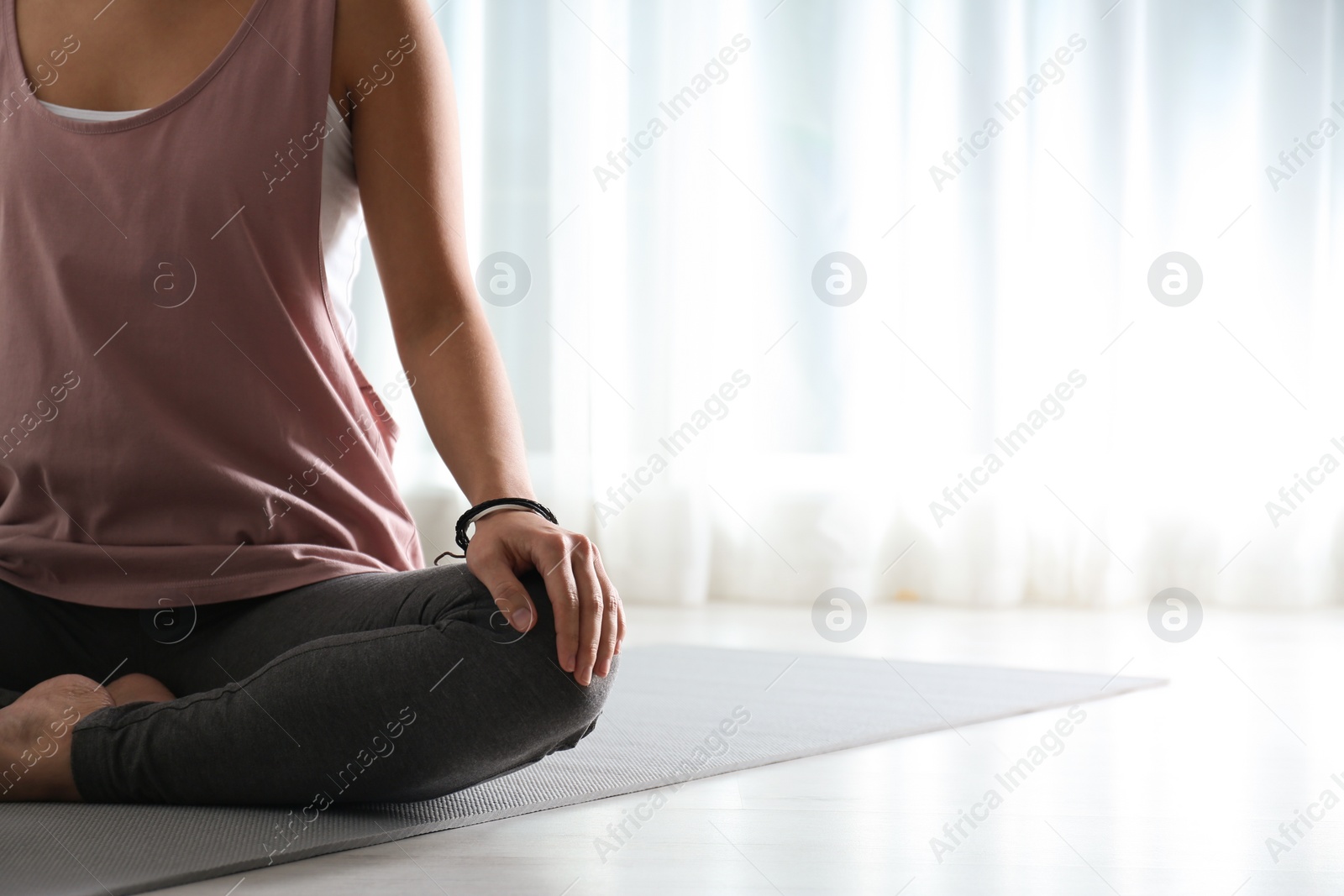 Photo of Woman practicing yoga on floor indoors, closeup. Space for text