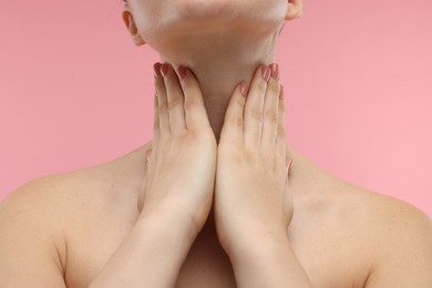 Woman touching her neck on pink background, closeup