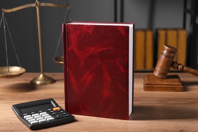 Photo of Tax law. Book, calculator, scales and gavel on wooden table