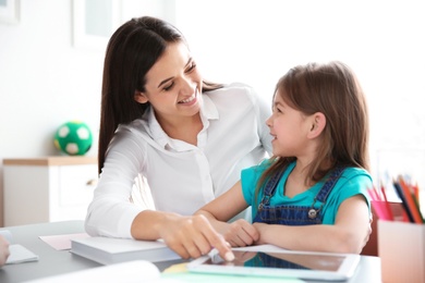 Female teacher helping girl with her task in classroom at school