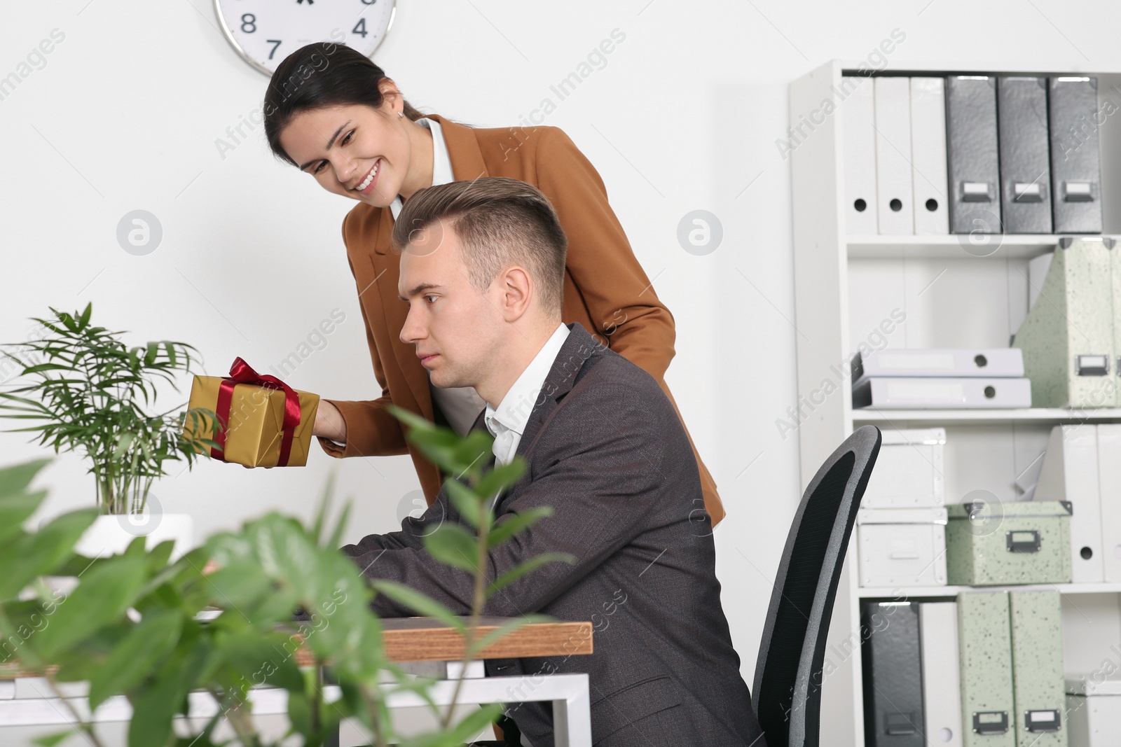 Photo of Woman presenting gift to her colleague in office