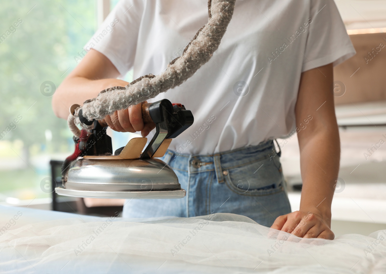 Photo of Female worker ironing laundry in dry-cleaning, closeup