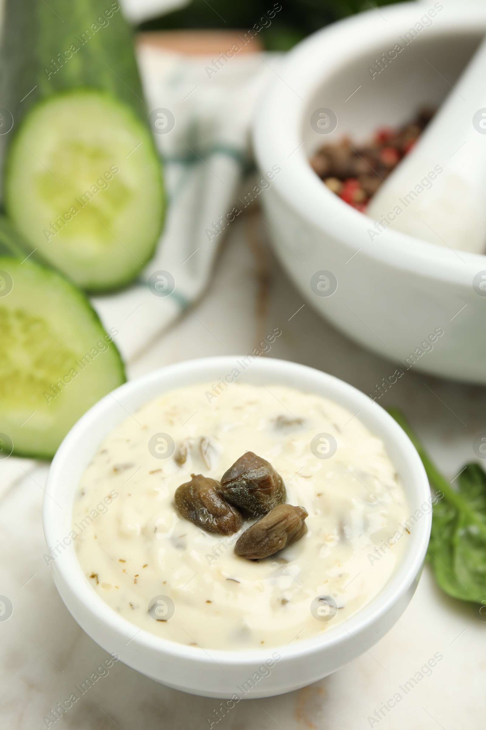 Photo of Creamy caper sauce in bowl on white table, closeup