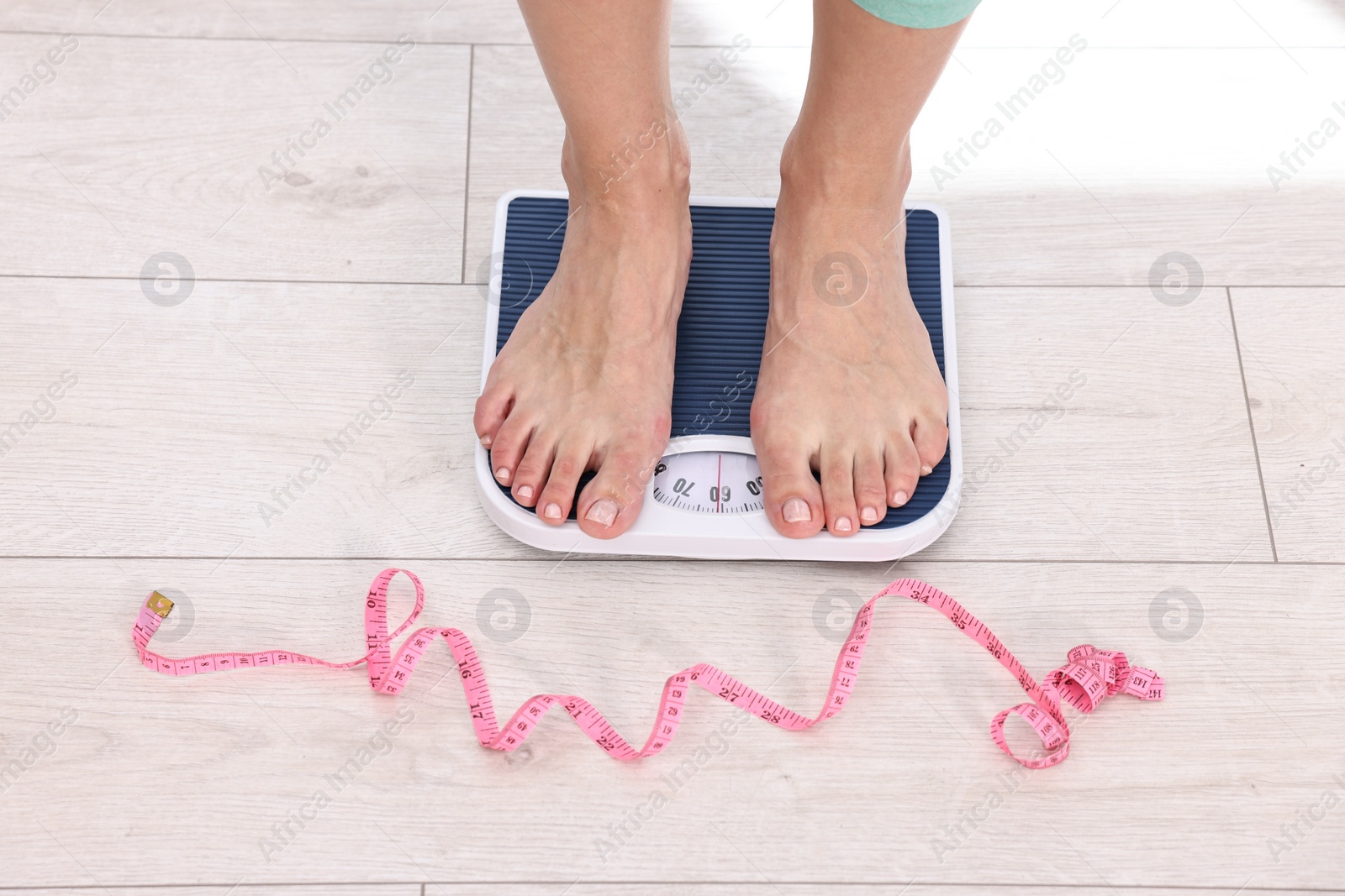 Photo of Woman on floor scale and measuring tape at home, closeup. Weight control